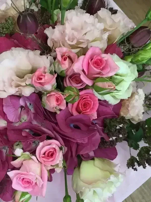 Bouquet of pink and purple roses, white lisianthus, and green accents.