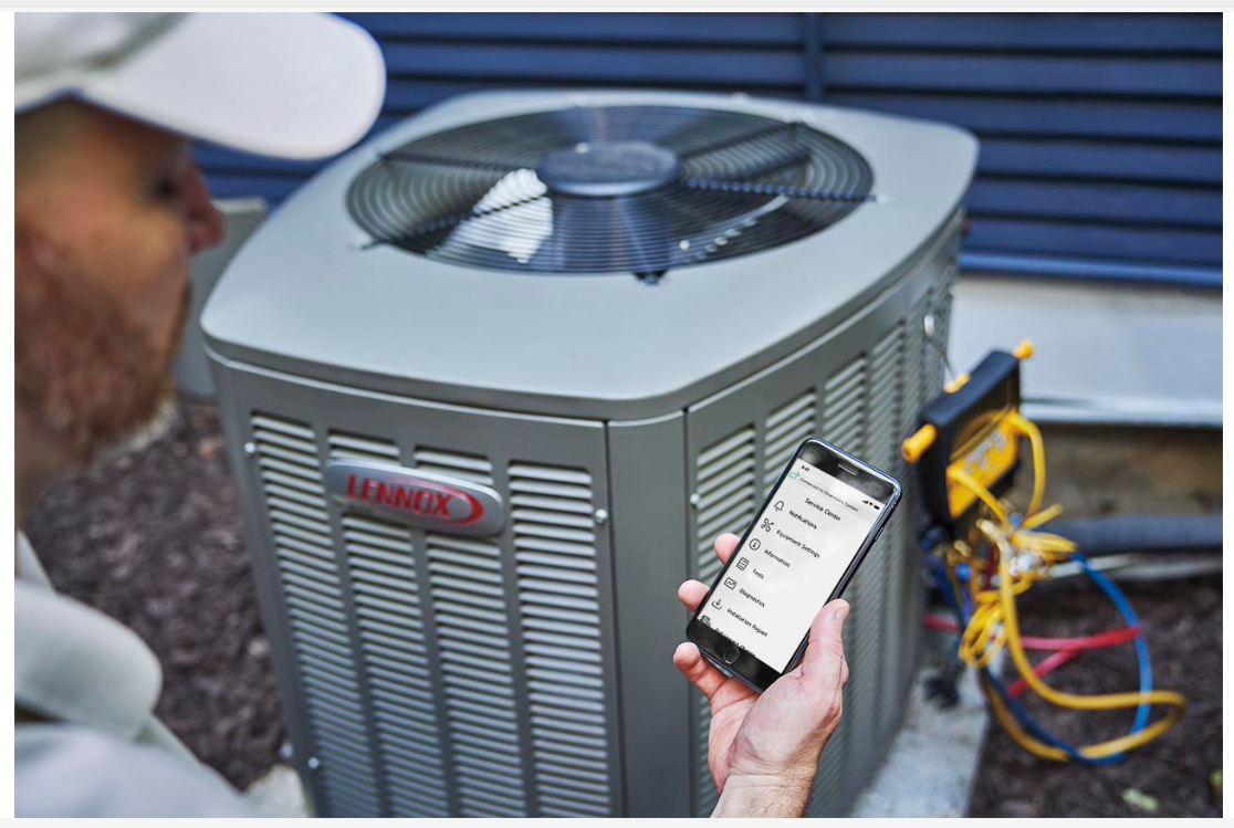 HVAC technician servicing an air conditioner; a gauge is connected with yellow, blue, and red hoses.