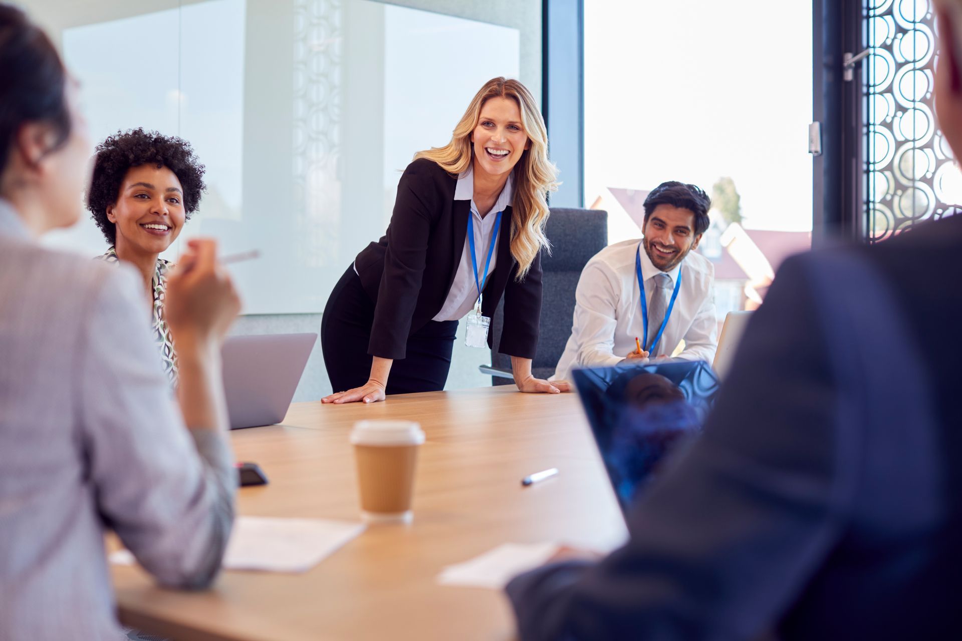 A diverse team of professionals in business attire collaborating at a bright, modern office conference table.