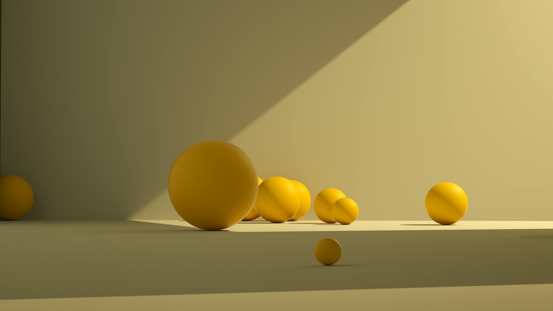 A collection of yellow spheres of varying sizes scattered on a flat surface against a softly lit wall.