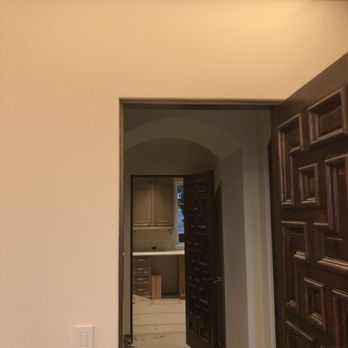 A partially open dark-stained, paneled wooden door looks into a hallway with another wooden door leading to a room.