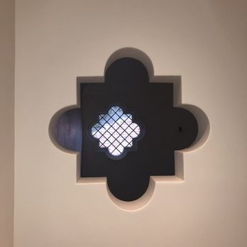 A recessed wall niche shaped like a quatrefoil, containing a smaller, diamond-latticed window that lets in light.
