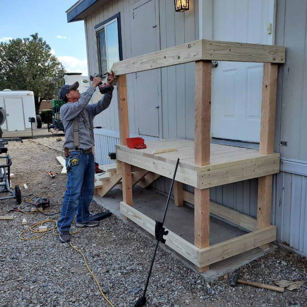 A man is working on a wooden structure outside of a house