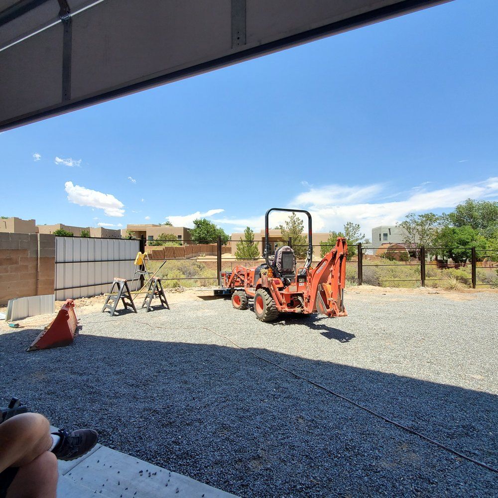 An orange tractor is parked in a gravel lot