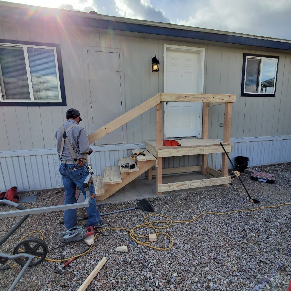 A man is standing in front of a mobile home building stairs.