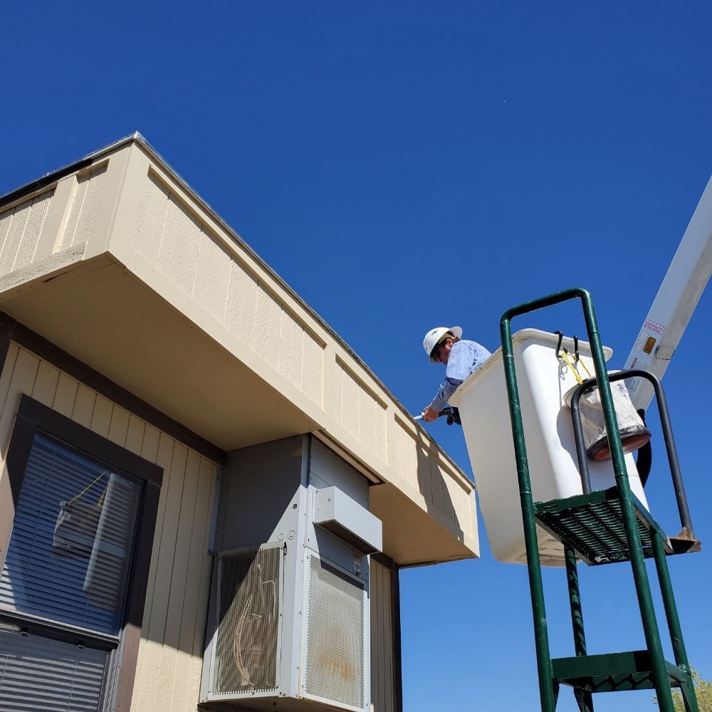 A man in a bucket is working on the side of a building