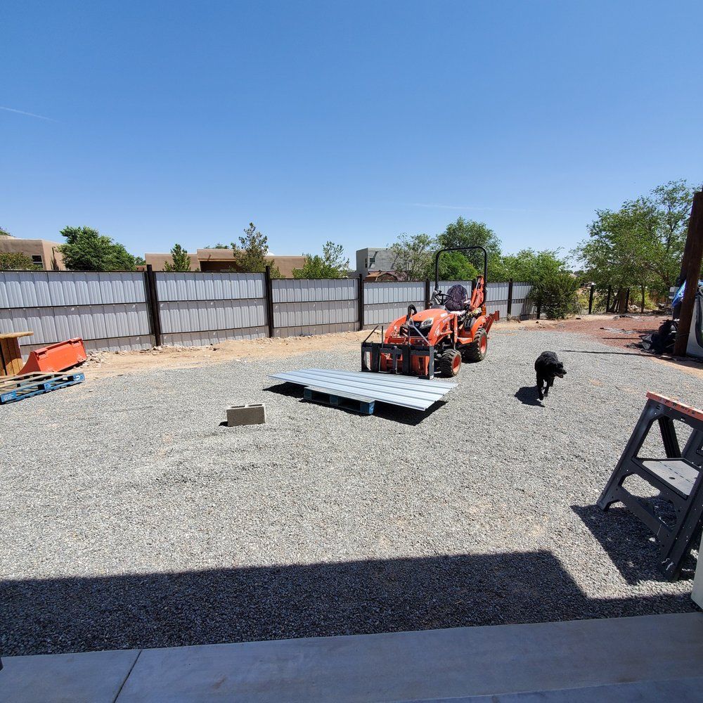 A dog standing next to a tractor in a gravel yard
