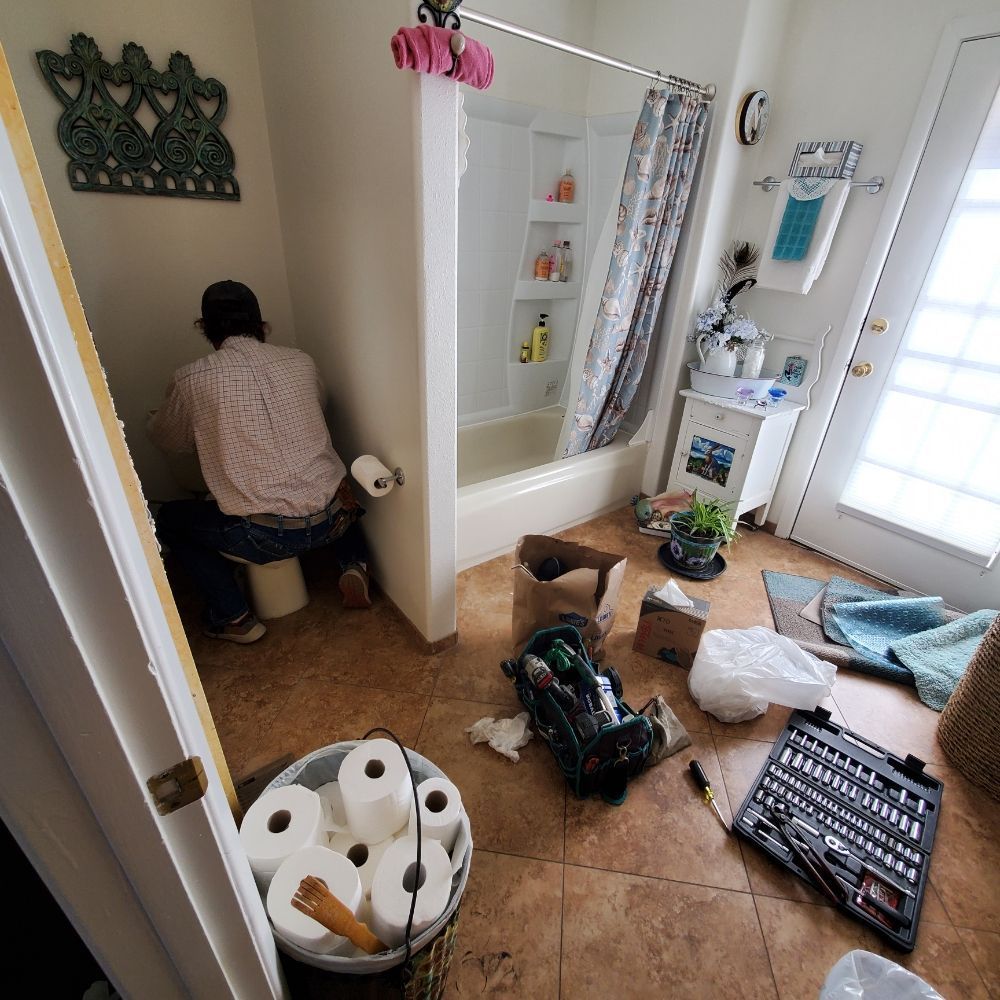A man is sitting on a toilet in a bathroom