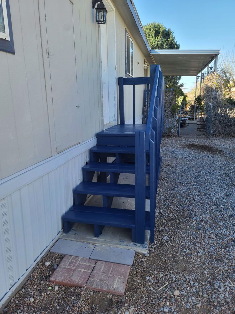A mobile home with blue stairs and a porch.