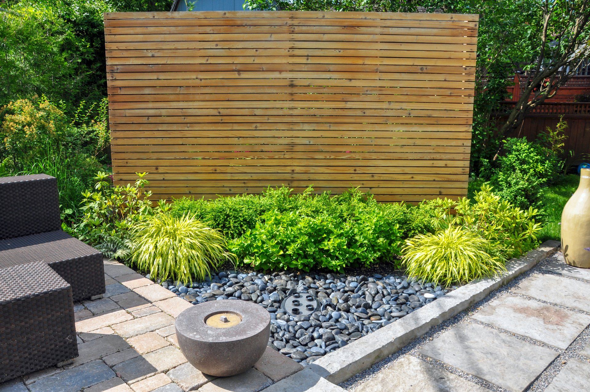 Beach pebbles, square cut flagstone and brick landscape pavers and simple plantings provide ample texture and contrast in this small contemporary backyard Asian inspired urban garden.