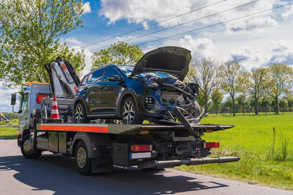 Tow Truck Carrying a Heavily Damaged Blue Car — Prompt Tilt Tray Towing & Recovery in Palmerston, NT