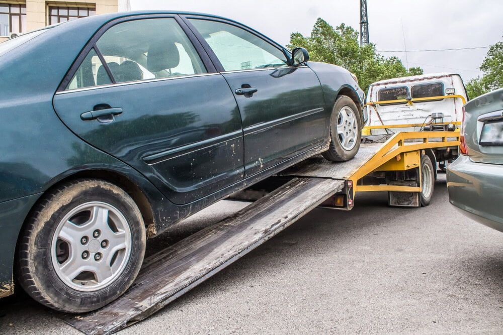 Green Sedan Being Towed Onto a Flatbed Tow Truck — Prompt Tilt Tray Towing & Recovery in Nightcliff, NT