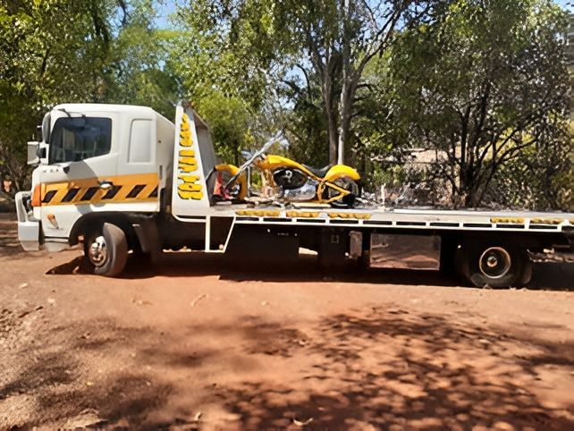 A Yellow Motorcycle Loaded on a White Tow Truck Parked — Prompt Tilt Tray Towing & Recovery in Herbert, NT