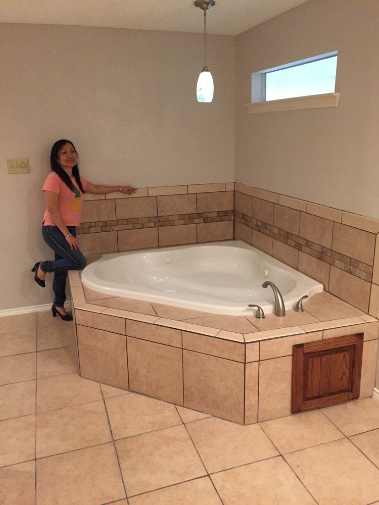 A woman is standing next to a jacuzzi tub in a bathroom.