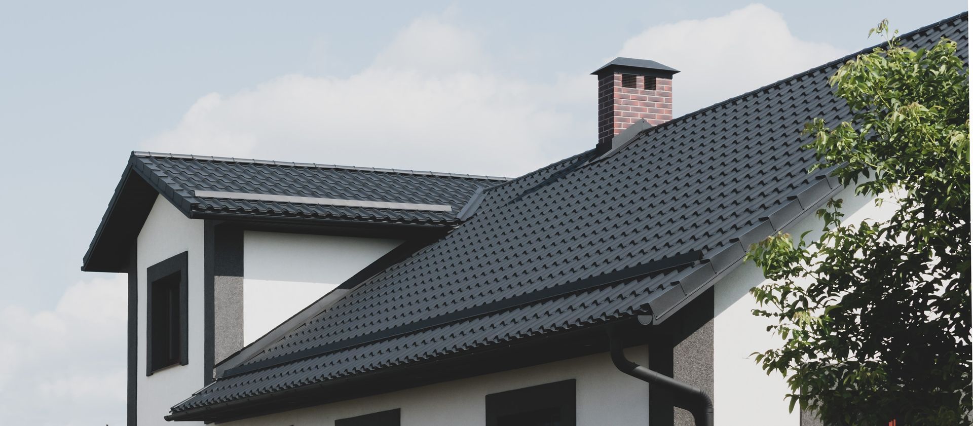 A white house with a black roof and a chimney.