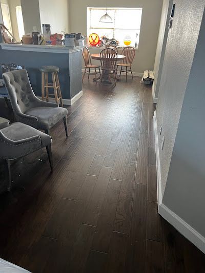 A living room with hardwood floors , chairs , a table and a window.