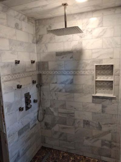 A man is installing tiles on a wall in a bathroom.