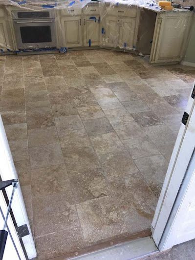 A kitchen with tile floors and white cabinets is being remodeled.