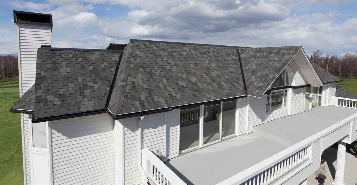 An aerial view of a large white house with a gray roof.