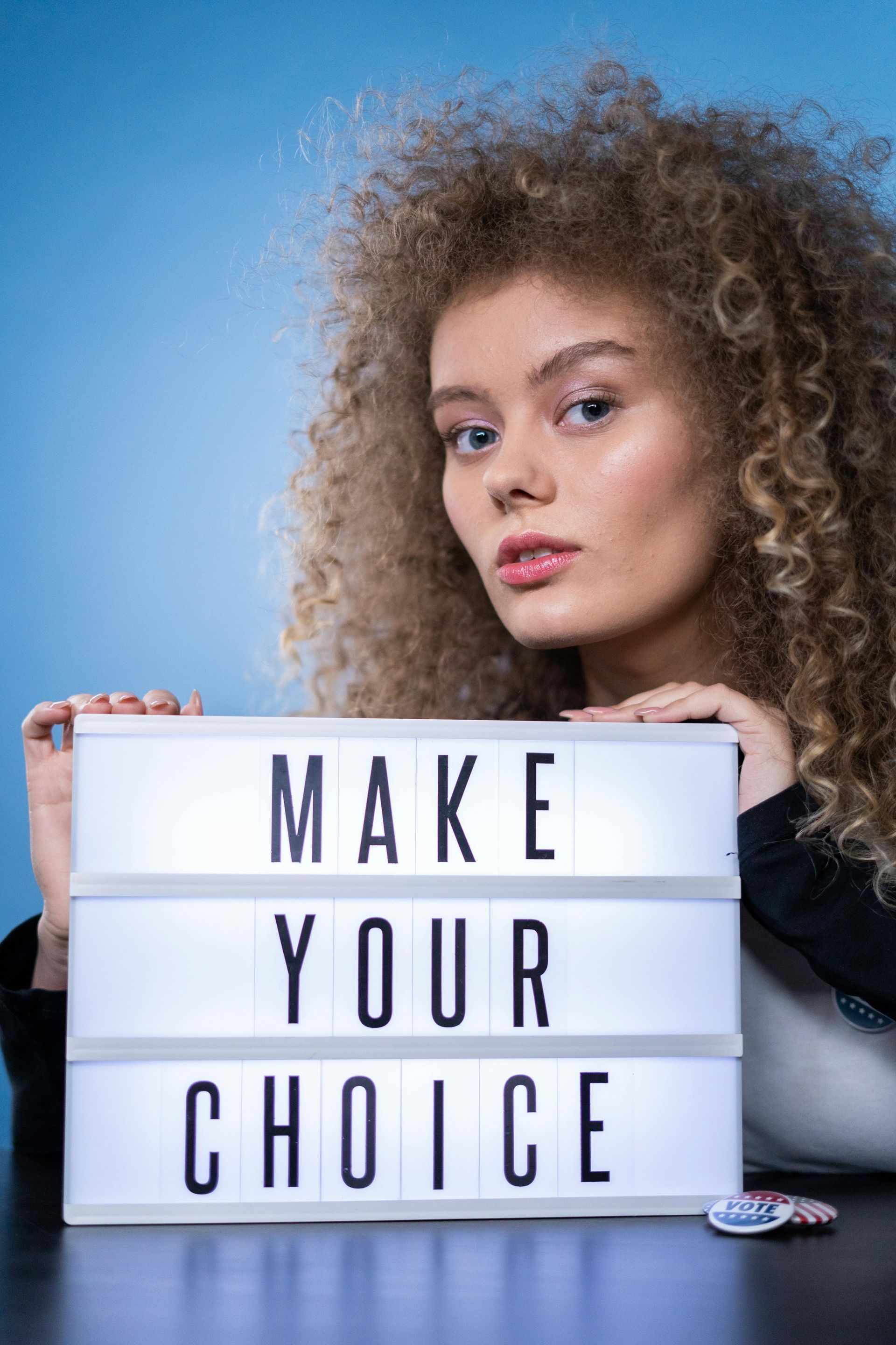 A woman is holding a light box that says `` make your choice ''.