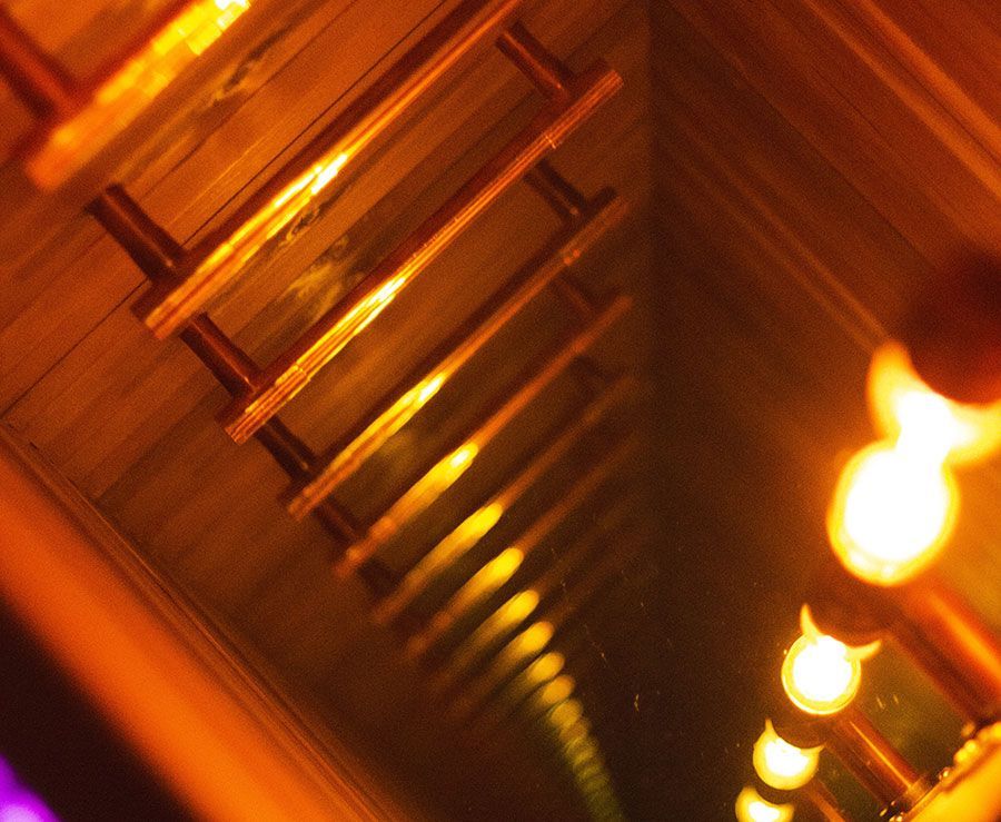 Illuminated tunnel with repeating wooden rungs and warm, orange lighting.