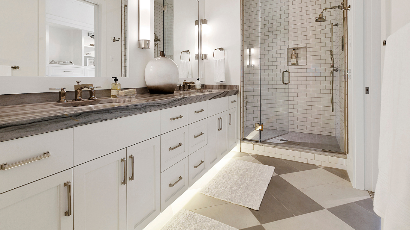 Hands using a compass on a blueprint. Sunlight illuminates a table with a hard hat, level, and glasses.