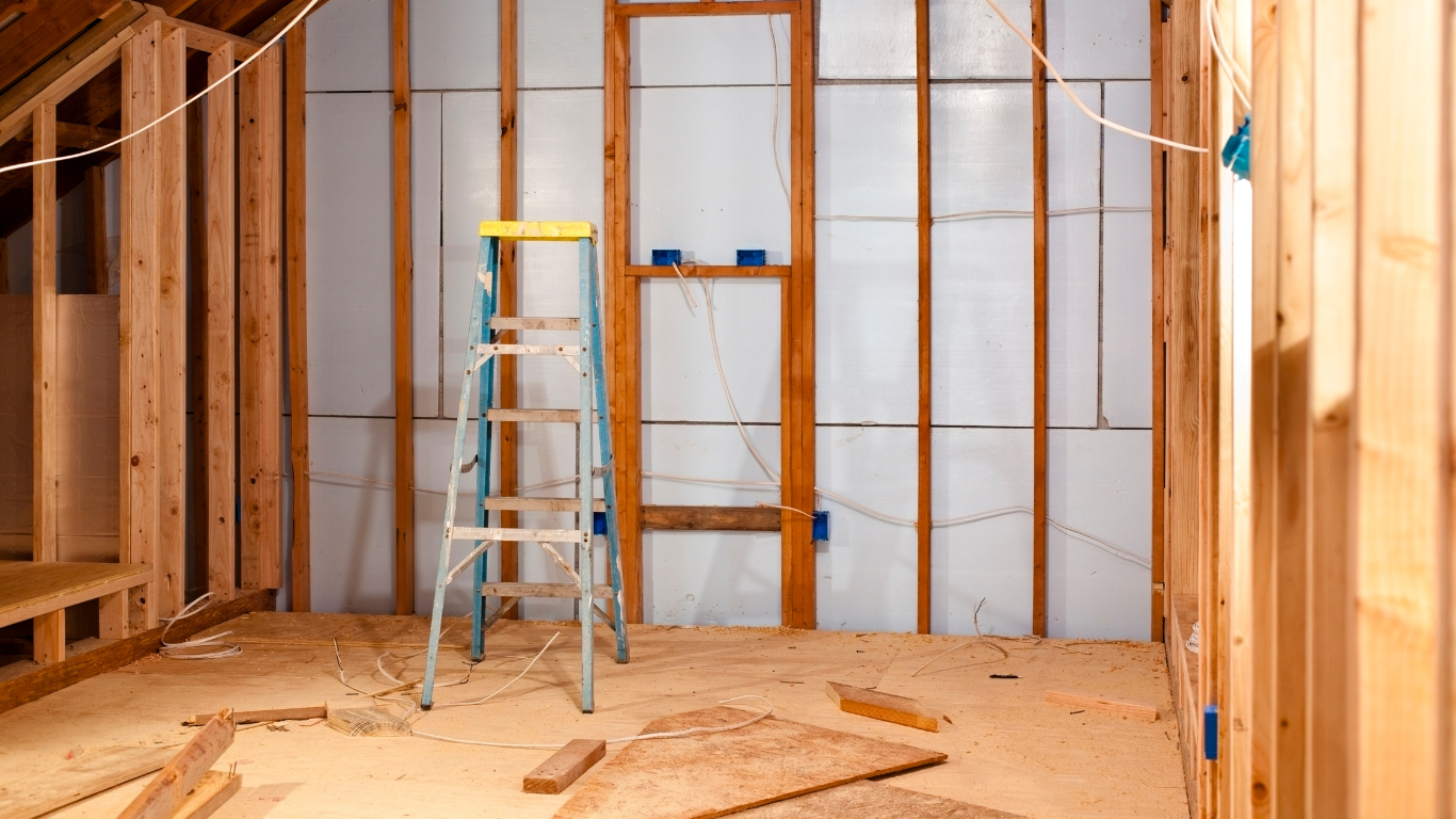 Spacious room with wood floor, fireplace, and French doors leading outside; light-filled interior.