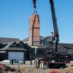 A crane is lifting a large wooden box on top of a truck.