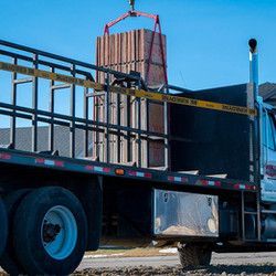 A truck is carrying a large piece of wood on the back of it.