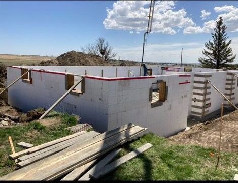 A house is being built in a field with a crane in the background.