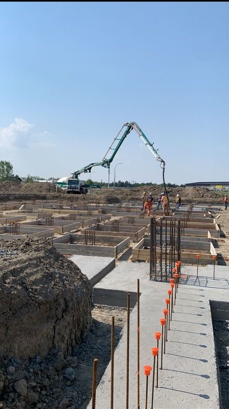 A construction site with a crane pumping concrete into the ground.