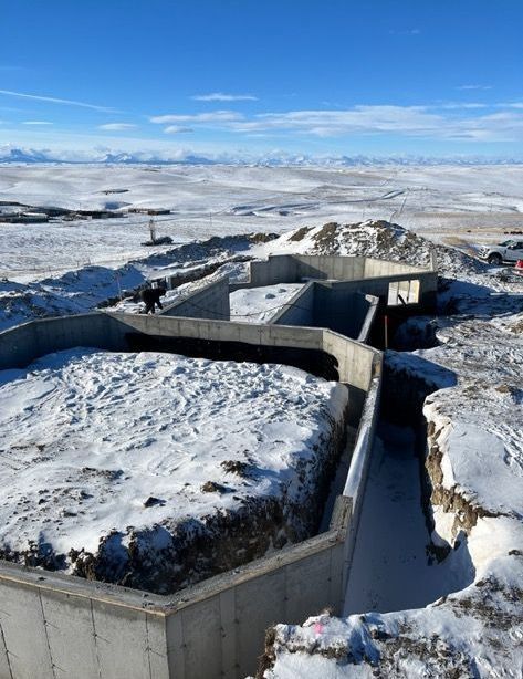 A snowy landscape with a concrete structure in the foreground