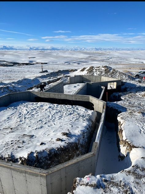 A large concrete structure is being built in the middle of a snowy field.