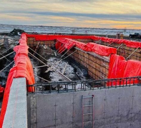 A large concrete wall is being covered with red tarps.