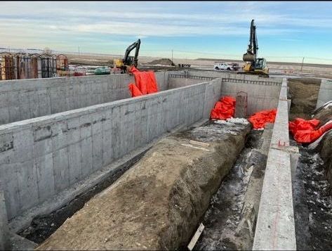 A large rock is sitting in the middle of a construction site.