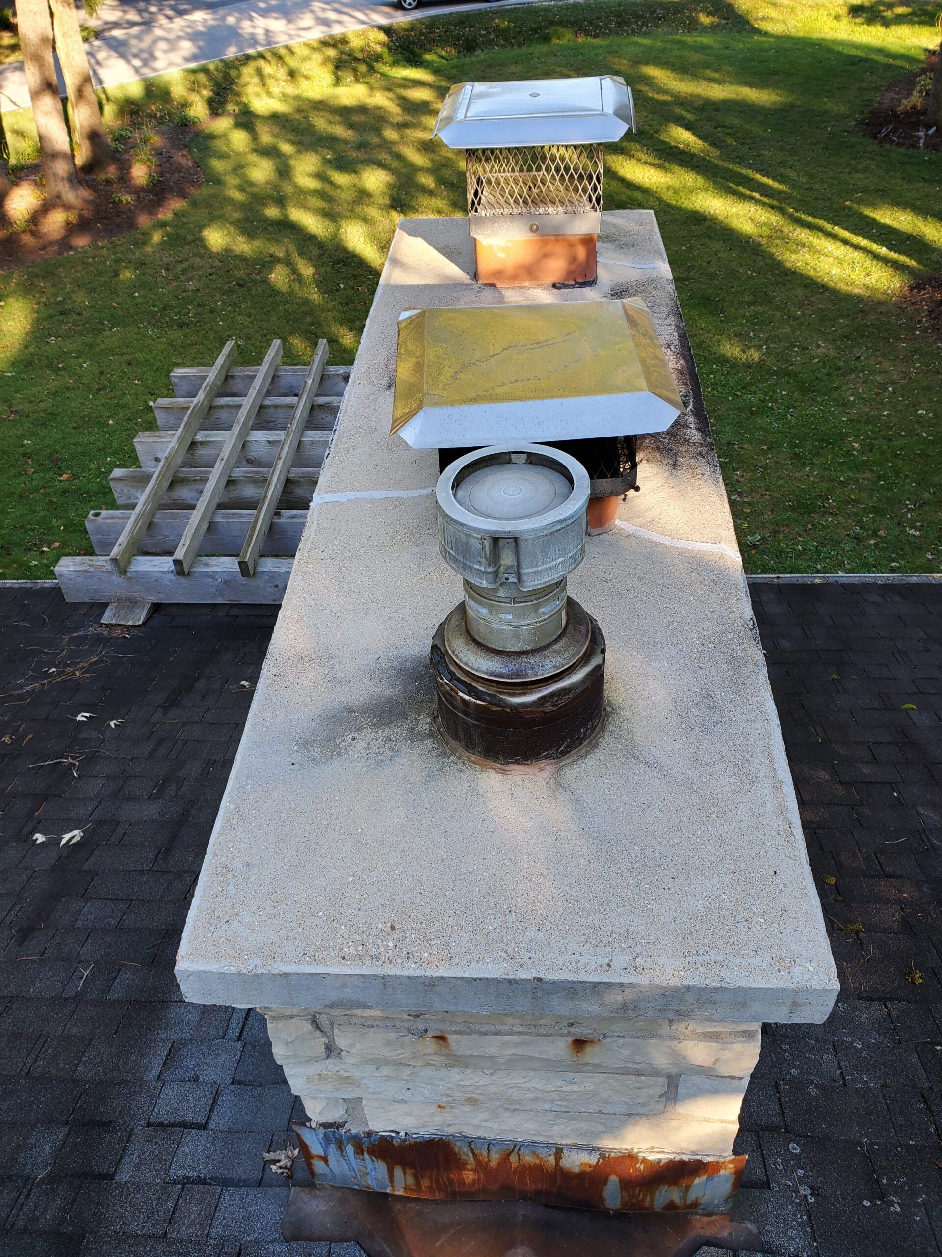 A chimney is sitting on top of a brick pillar on a roof.