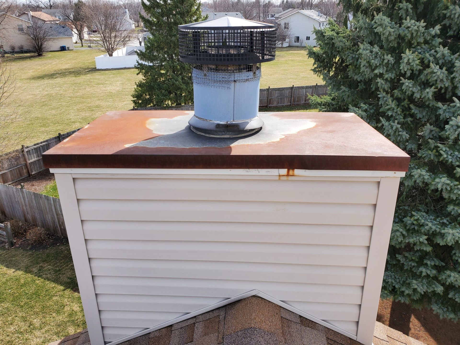 A chimney on top of a white house with a copper roof.