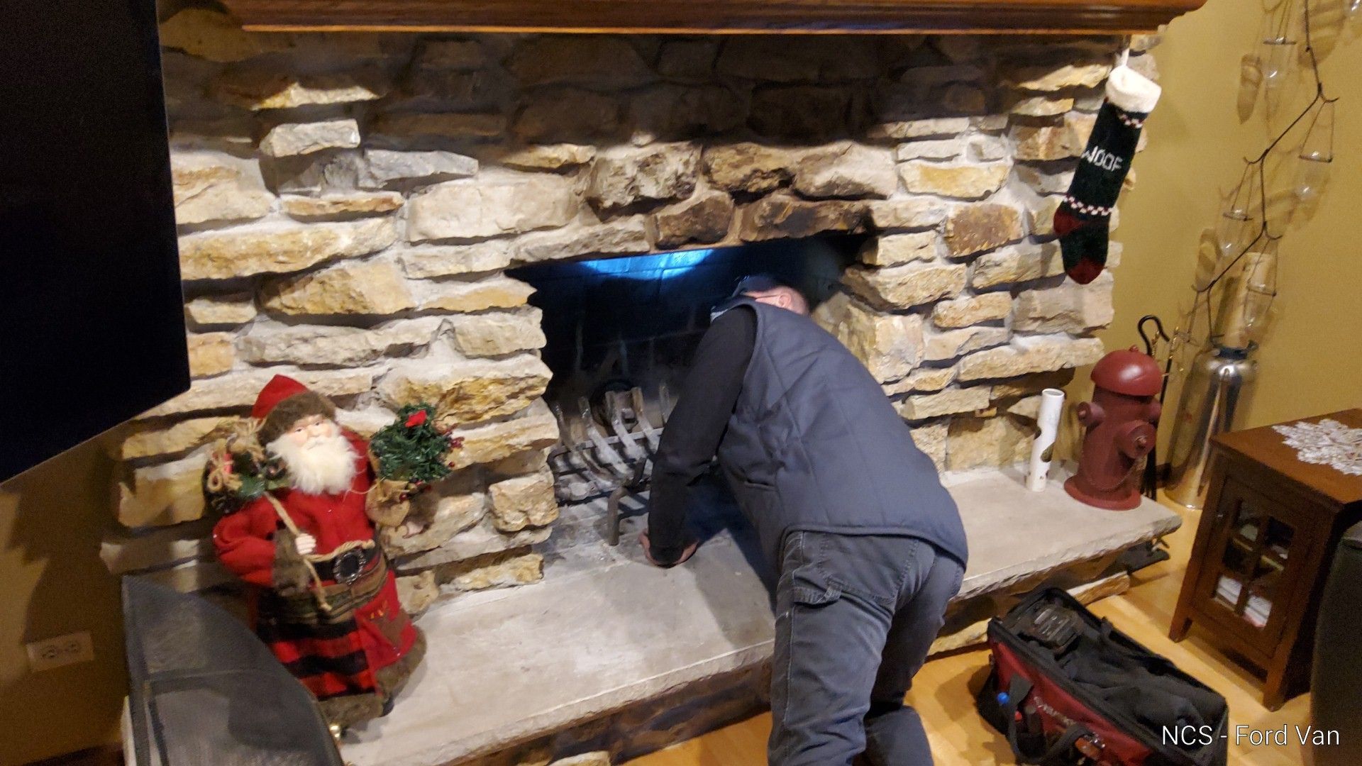 A man is working on a fireplace in a living room.