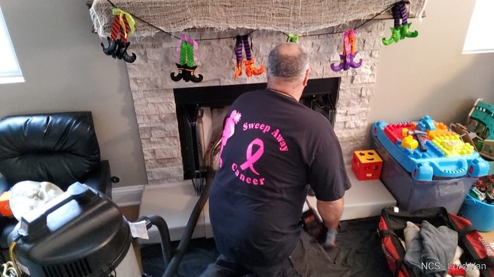 A man is cleaning a fireplace with a vacuum cleaner in a living room.