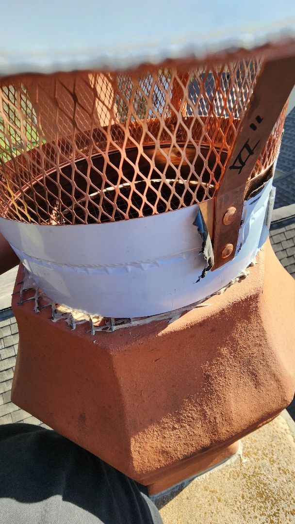 A person is holding a white object on top of a brick chimney.
