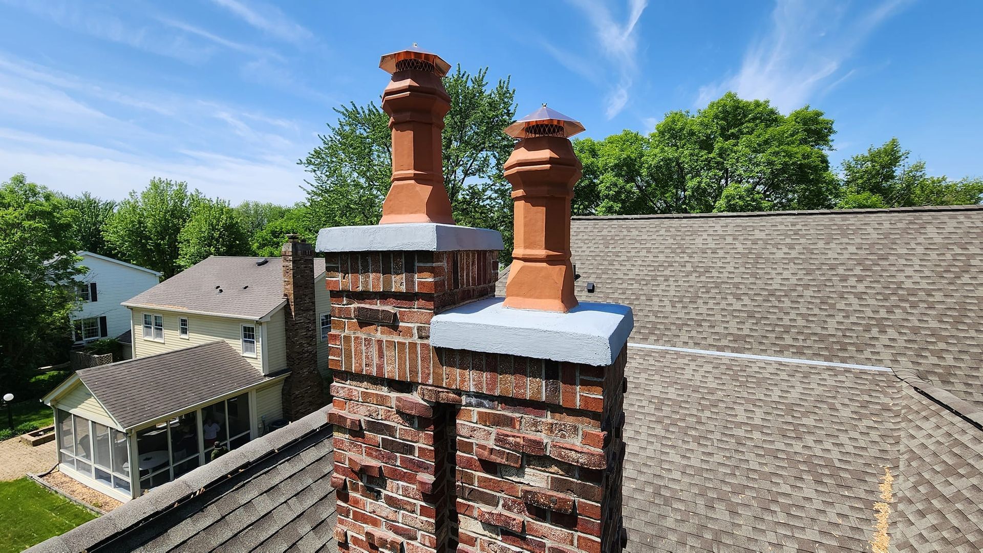 A brick chimney on top of a roof next to a house.