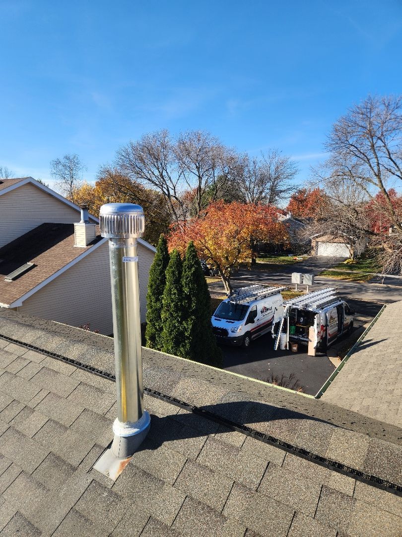 A brick chimney on top of a roof next to a house.