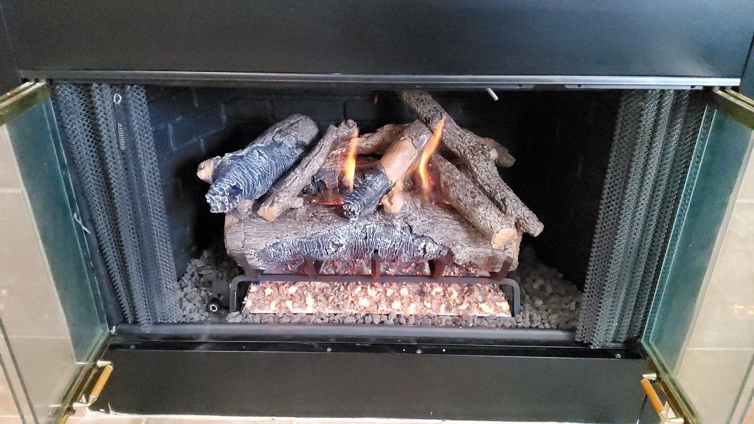 Gas fireplace with lit faux logs, set inside a black-framed enclosure with green trim.