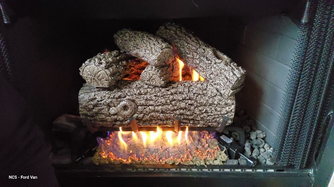 Gas fireplace with burning flames and decorative ceramic logs.