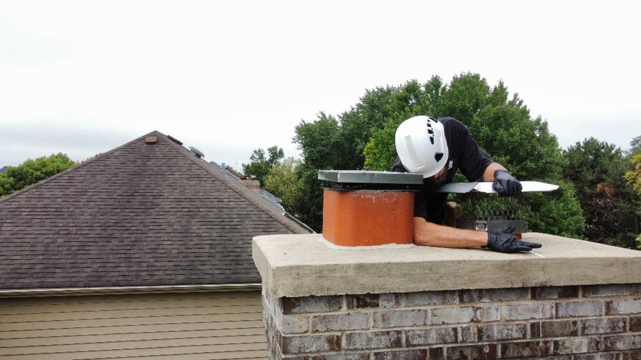 A man is standing on top of a brick chimney.
