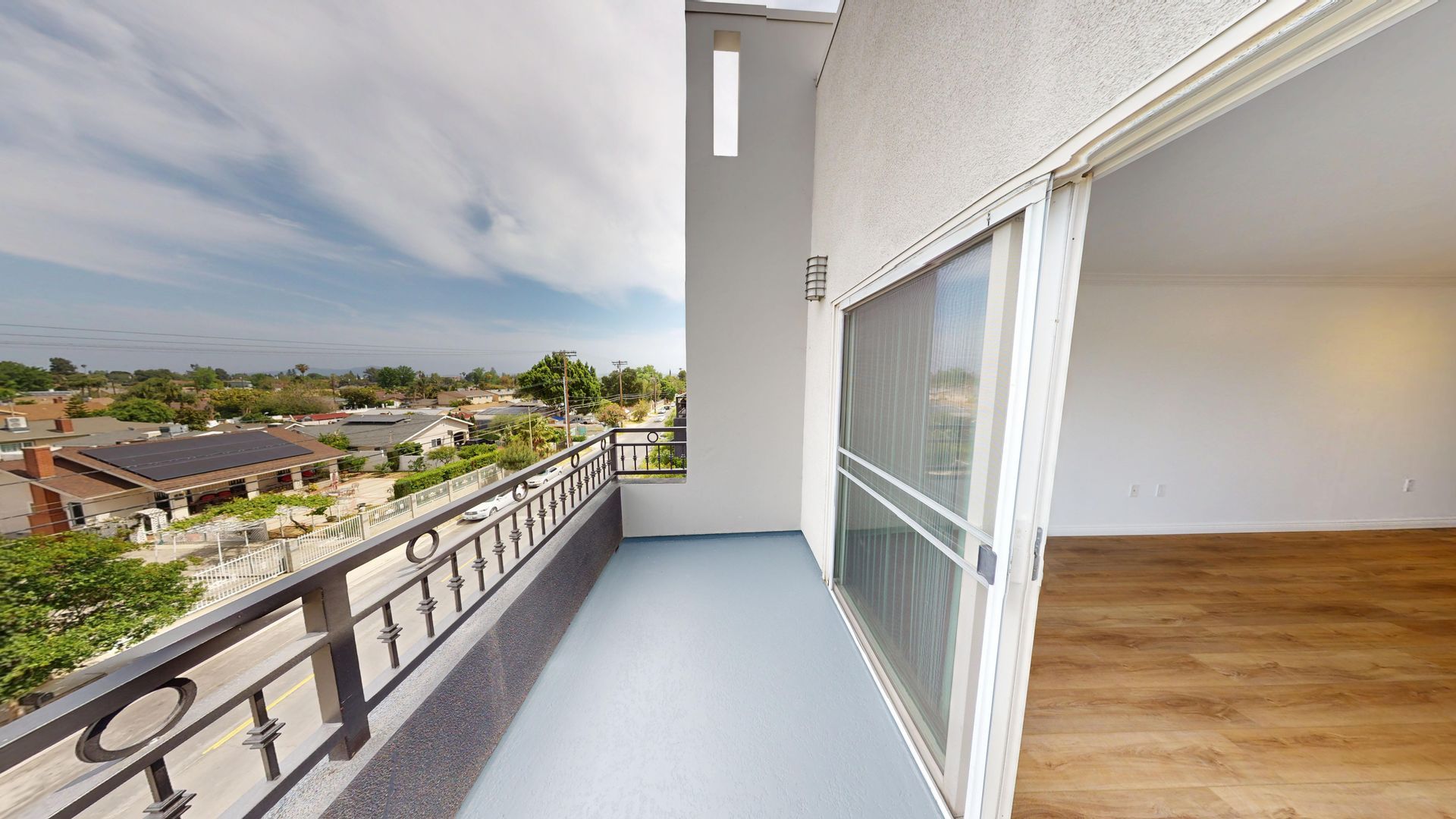 Balcony with view: Buildings, blue sky, and a sliding glass door.