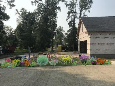 A colorful garden of various flowers in front of a house under construction.