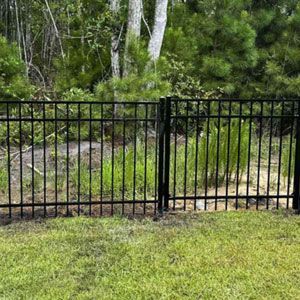 Black metal fence in front of greenery.