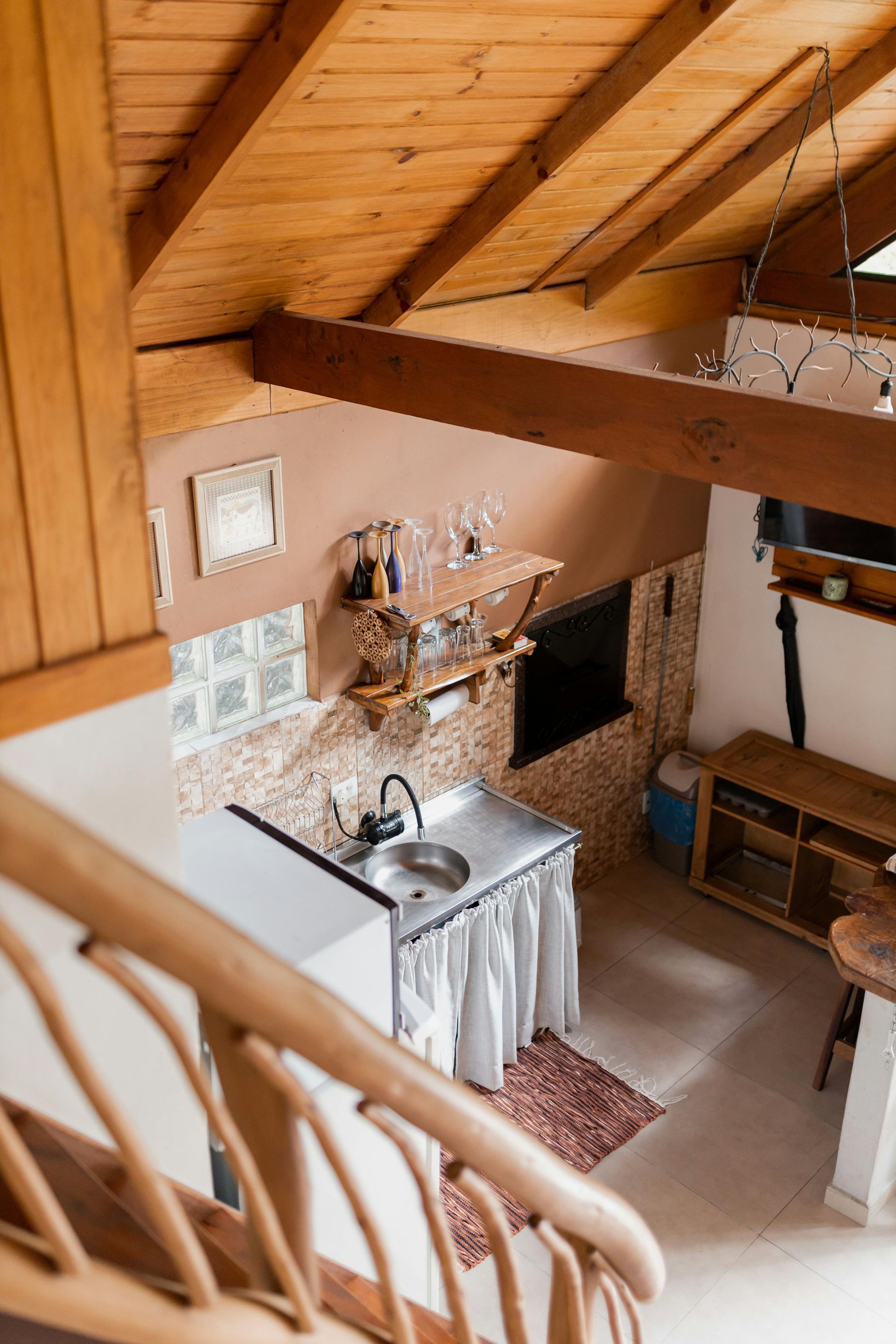 An aerial view of a kitchen with a wooden ceiling and stairs leading to it.