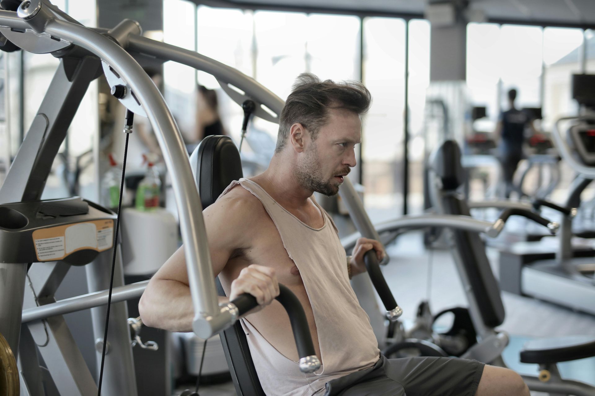 A man is sitting on a machine in a gym.